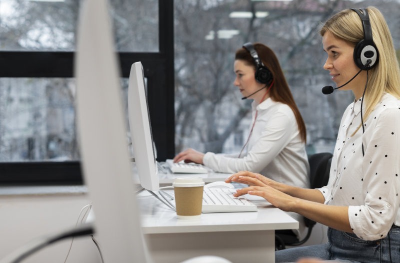 Female workers in office wearing telephone headsets